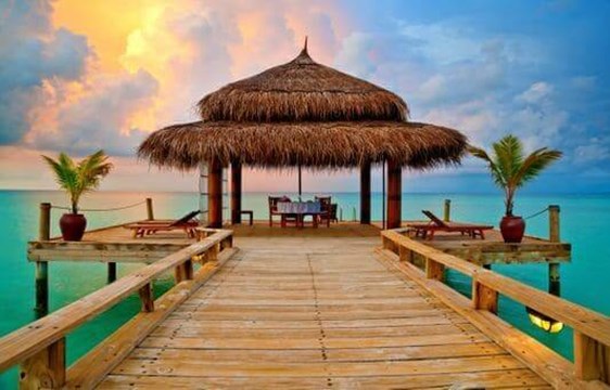 sunset over a tropical overwater hut in the maldives
